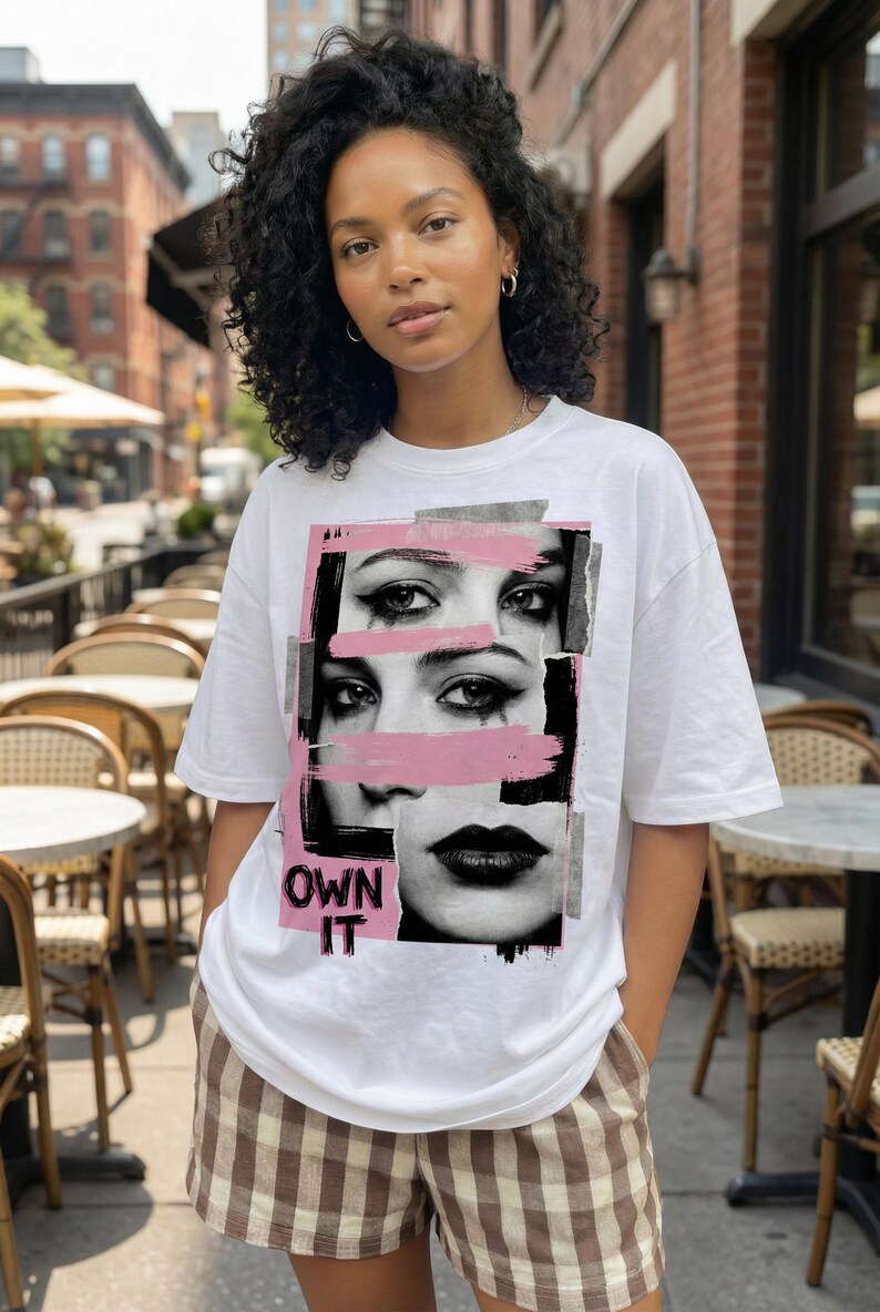 Women’s “Own It” face collage t-shirt design with pink brush stroke overlays and edgy streetwear aesthetic on white tee
