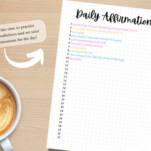 May include: A white sheet of paper with a dotted pattern and the text "Daily Affirmation" at the top. The paper is numbered from 1 to 31 and has a list of affirmations to write in. The paper is on a wooden surface with a cup of coffee.