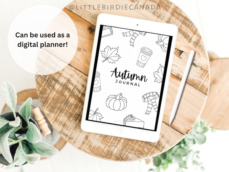 K&ouml;nnte beinhalten: Ein wei&szlig;es Tablet mit einem "Autumn Journal"-Design mit herbstlichen Illustrationen, darunter Bl&auml;tter, ein K&uuml;rbis und ein Schal. Das Tablet liegt auf einer Holzoberfl&auml;che, daneben ein Stift. Der Text auf dem Tablet lautet "Can be used as a digital planner!"