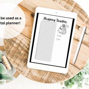 May include: A black and white digital planner with a grid and the text "Shopping Tracker". A drawing of shopping bags is on the right side of the page. The planner is on a wooden surface.