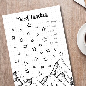 May include: A black and white mood tracker printable featuring a mountain range and stars. The printable includes a checklist with the following options: energetic, happy, ok, tired, sad, angry.
