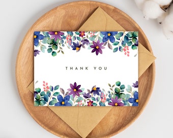 May include: A white card with a watercolor floral border in shades of purple, blue, and green. The text "THANK YOU" is printed in black in the center of the card.