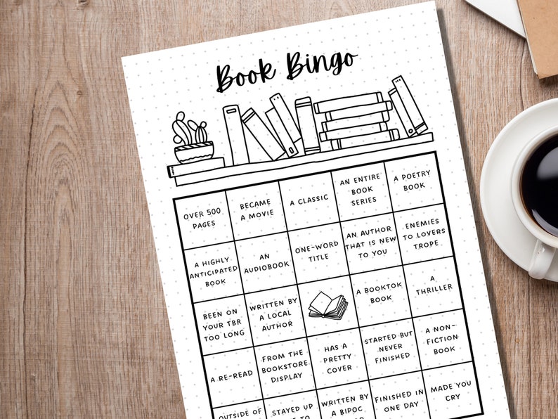 May include: Black and white Book Bingo game sheet with a bookshelf illustration at the top. The bingo card includes squares with prompts like "Over 500 Pages," "A Classic," and "A Thriller." A cup of coffee sits to the right.