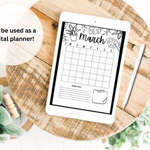 May include: A digital planner with a black and white design featuring a calendar for the month of March, a section for monthly goals, and a notes section. The calendar is decorated with a border of leaves and plants. The planner is displayed on a wooden table.