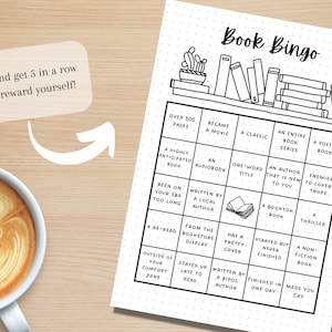 May include: Black and white "Book Bingo" game sheet with a coffee cup in the corner. The bingo card has squares with book-related prompts. Text on the sheet includes "Try and get 5 in a row and reward yourself!"