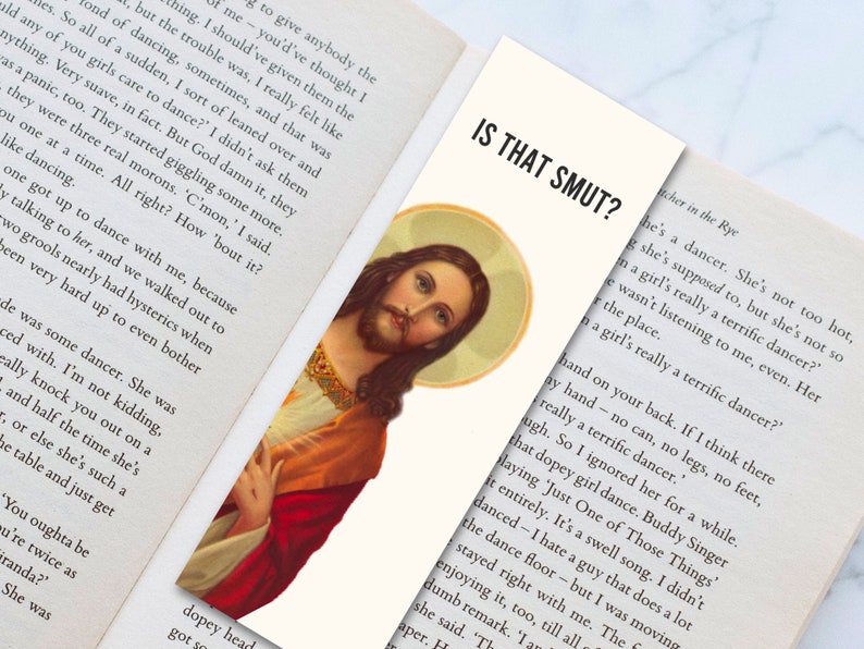 May include: A close-up of a painting of Jesus Christ with a red robe and a crown of thorns. The painting is framed in a white border and has a text overlay that reads "Is That Smut?"