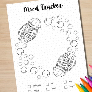 Może przedstawiać: Czarno-biały, drukowalny tracker nastroju z motywem meduzy. Tracker ma koło baniek z numerami od 1 do 8. Tekst "Mood Tracker" znajduje się na g&oacute;rze strony. Pod kołem znajdują się pola wyboru z napisami "energetyczny", "szczęśliwy", "ok", "zmęczony", "smutny" i "zły".
