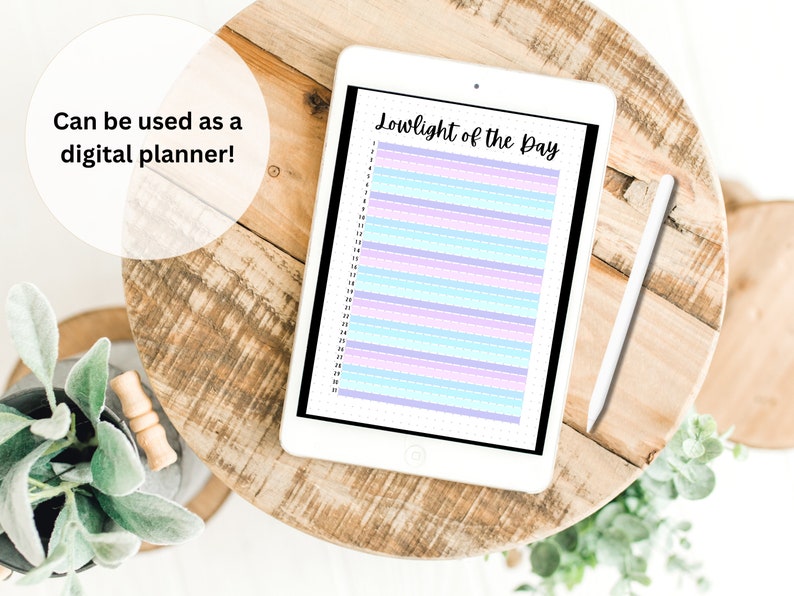 May include: A digital planner on a tablet with the text "Lowlight of the Day" and a white stylus on a wooden table. The planner has a light blue, pink, and purple striped design.