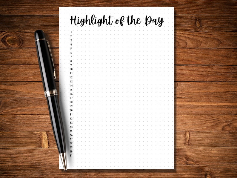 Puede incluir: Una hoja de papel blanca con el texto "Highlight of the Day" en la parte superior. El papel est&aacute; dividido en 31 secciones numeradas, cada una con una cuadr&iacute;cula de peque&ntilde;os puntos. Un bol&iacute;grafo negro est&aacute; al lado del papel.