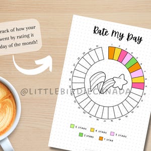 K&ouml;nnte beinhalten: Ein wei&szlig;es, gepunktetes Papier mit dem Text "Rate My Day" und einer farbenfrohen Sterntabelle zur Verfolgung t&auml;glicher Bewertungen. Die Tabelle enth&auml;lt eine Sterngrafik und den Text "Verfolgen Sie, wie Ihr Tag verlaufen ist, indem Sie ihn jeden Tag des Monats bewerten!"