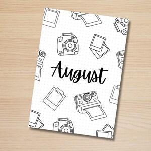 May include: A white printable planner page with a black and white camera pattern and the word "August" in black text.