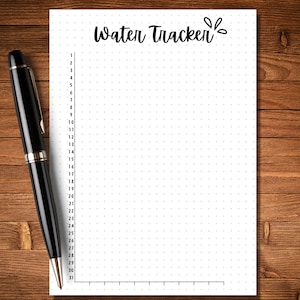 May include: A white sheet of paper with a dotted grid pattern and the text "Water Tracker" written in black cursive. A black pen is lying on a wooden surface next to the paper.