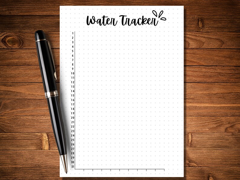May include: A white sheet of paper with a dotted grid pattern and the text "Water Tracker" written in black cursive. A black pen is lying on a wooden surface next to the paper.