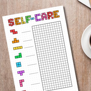 May include: A white self-care planner sheet with the words "SELF-CARE" in colorful pixelated letters. Below the title are colorful Tetris-like shapes. The sheet has a grid for tracking and is on a wooden surface.