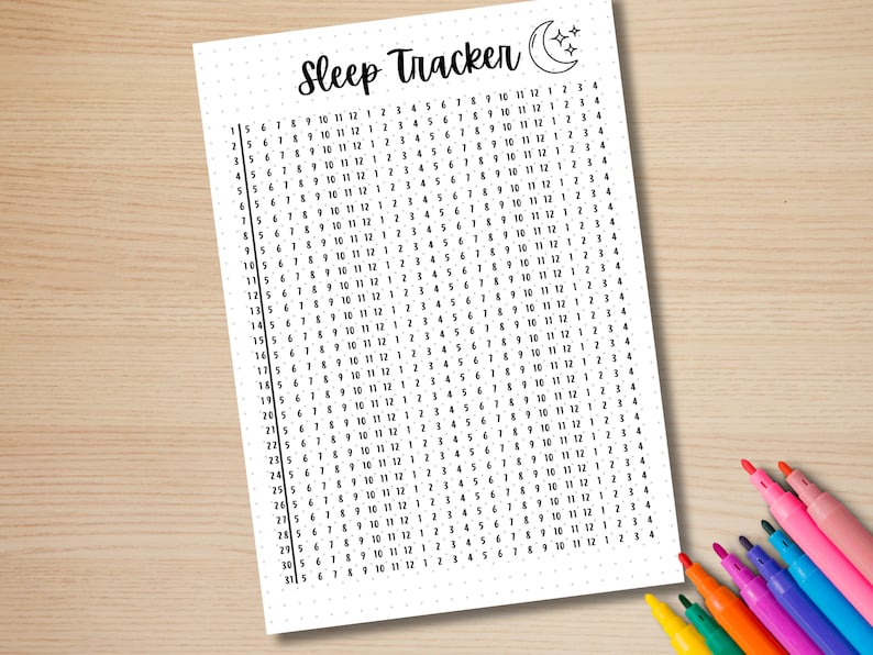 Może przedstawiać: Biały wykres śledzenia snu z kropkowaną siatką, z tytułem "Sleep Tracker" i ilustracją p&oacute;łksiężyca i gwiazd. Wykres jest wypełniony liczbami i towarzyszą mu kolorowe markery na drewnianej powierzchni.