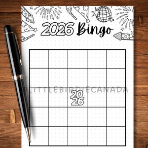 May include: A black pen lies next to a white bingo card. The card has a grid and the text "2026 Bingo." The top of the card features illustrations of fireworks and party hats. The background is a wooden surface.