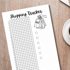 May include: A black and white printable shopping tracker with a grid for each month of the year and a checklist on the right side. The illustration at the top shows a hand holding shopping bags with the word "SALE" on one of the bags.