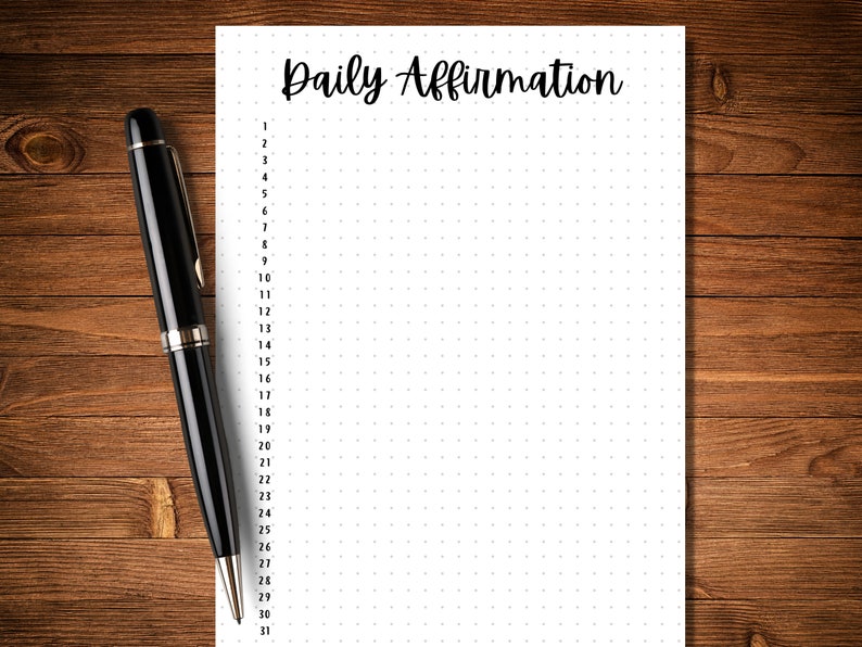 May include: A white sheet of paper with the words "Daily Affirmation" at the top. The paper is divided into 31 numbered sections, each with a dotted grid pattern. A black pen is lying next to the paper.