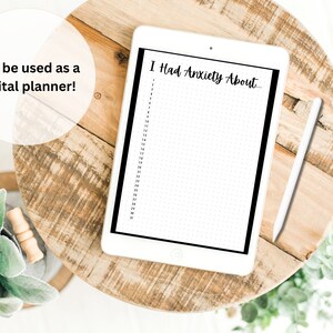 以下が含まれることがあります： 黒い縁取りのある白いデジタルタブレットに、「I Had Anxiety About...」というテキストと番号付きの行が書かれた印刷可能なプランナーページが表示されています。タブレットは木製の表面に置かれ、その横に白いスタイラスがあります。