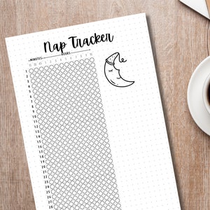 May include: A black and white Nap Tracker printable sheet with a dotted background. The sheet includes a sleep tracker with circles to fill in, and a drawing of a sleeping moon. A cup of coffee sits on a saucer in the background.