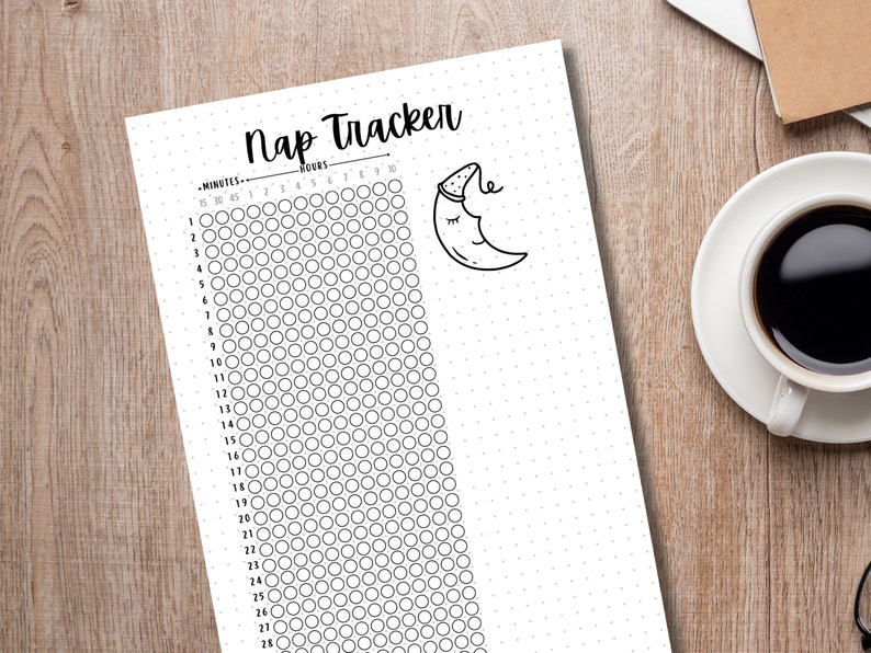 May include: A black and white Nap Tracker printable sheet with a dotted background. The sheet includes a sleep tracker with circles to fill in, and a drawing of a sleeping moon. A cup of coffee sits on a saucer in the background.