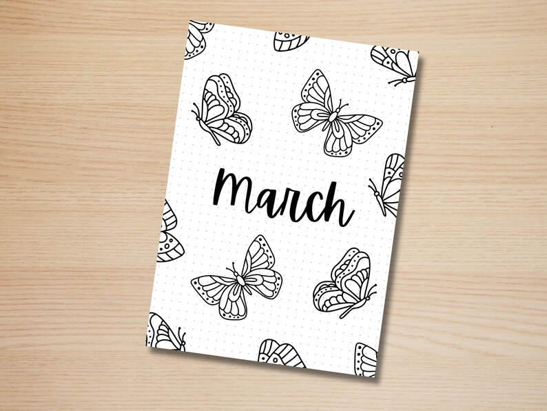 May include: A white notebook cover featuring a pattern of black butterfly illustrations and the word "March" in a handwritten font. The background is dotted.