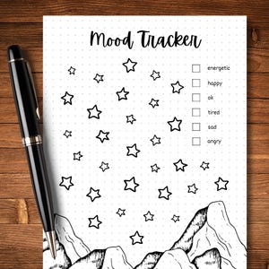 May include: A black and white printable mood tracker featuring a mountain and star design. The tracker includes a checklist with the following options: energetic, happy, ok, tired, sad, angry.
