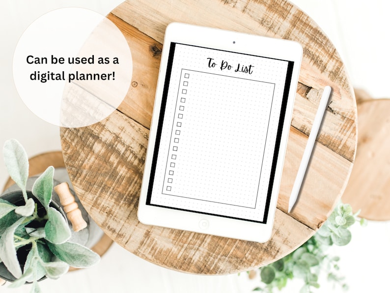 Op de afbeelding: Een witte tablet met een zwarte rand die een to-dolijst met vinkjes weergeeft. De tekst "To Do List" is geschreven in zwarte cursieve letters. De tablet ligt op een houten oppervlak met een witte stylus ernaast.