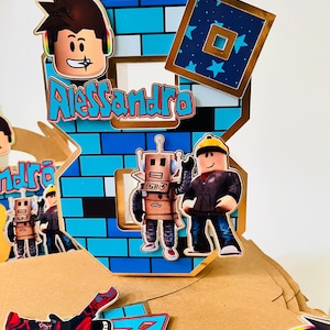 May include: A blue and gold Roblox themed cake topper with the number 8, a brick pattern, and the name Alessandro. The topper features Roblox characters, including a robot and a figure wearing a black jacket.