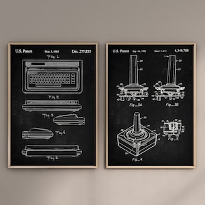 Könnte beinhalten: Zwei gerahmte Patentdrucke an einer Wand. Der linke Druck zeigt ein Tastaturdesign vom 5. März 1985. Der rechte Druck zeigt ein Joystick-Design vom 14. September 1982. Beide Drucke sind in Schwarzweiß gehalten.
