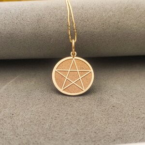 May include: A gold pendant necklace with a circular charm featuring a five-pointed star.