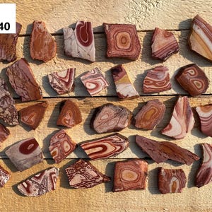 May include: A collection of 25 red, white, and brown banded agate stone slices. The stones are irregularly shaped and have a variety of patterns. The stones are labeled "Knobs 571-640".