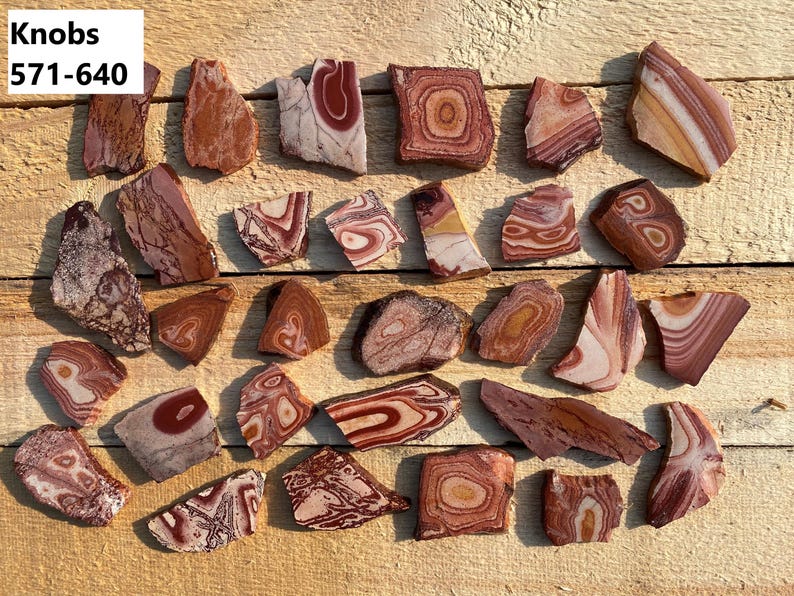 K&ouml;nnte beinhalten: Eine Sammlung von 25 roten, wei&szlig;en und braunen, geb&auml;nderten Achat-Steinscheiben. Die Steine sind unregelm&auml;&szlig;ig geformt und haben eine Vielzahl von Mustern. Die Steine sind mit "Knobs 571-640" beschriftet.