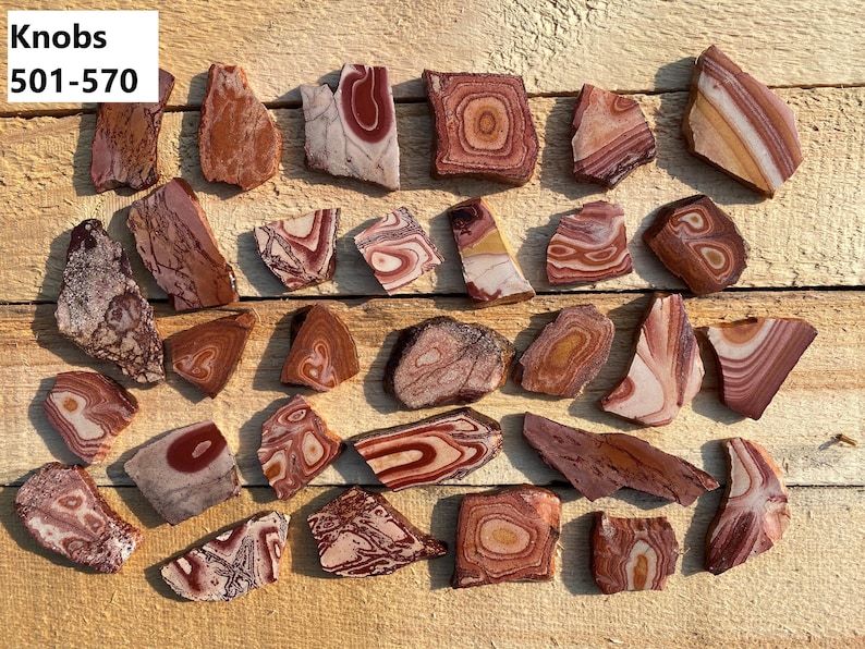 K&ouml;nnte beinhalten: Eine Sammlung von 25 rot, wei&szlig; und braun geb&auml;nderten Achat-Scheiben. Die Achat-Scheiben haben verschiedene Formen und Gr&ouml;&szlig;en. Die Achat-Scheiben sind mit "Knobs 501-570" beschriftet.