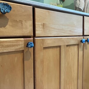 Peut inclure: Gros plan sur des portes d'armoire en bois avec des boutons de porte en forme de pierre bleue et noire.