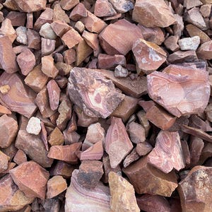 K&ouml;nnte beinhalten: Ein Haufen roter, brauner und wei&szlig; gestreifter Steine. Die Steine sind in verschiedenen Gr&ouml;&szlig;en und Formen.