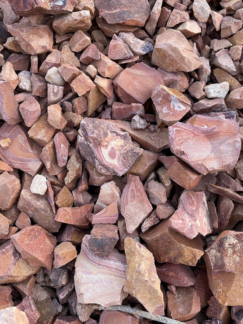 K&ouml;nnte beinhalten: Ein Haufen roter, brauner und wei&szlig; gestreifter Steine. Die Steine sind in verschiedenen Gr&ouml;&szlig;en und Formen.