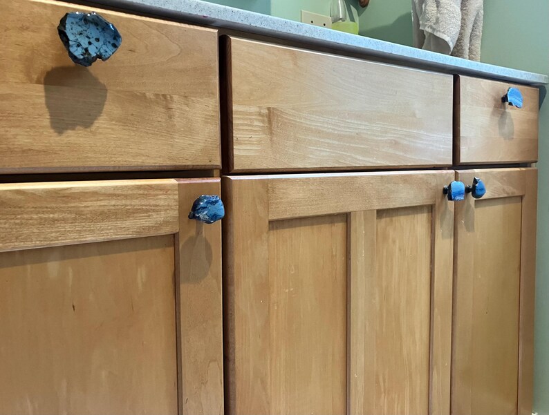Peut inclure: Gros plan sur des portes d'armoire en bois avec des boutons de porte en forme de pierre bleue et noire.