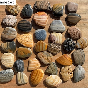 May include: A collection of 30+ decorative stone knobs in various shapes, sizes, and colors. The knobs are made of natural stone with striped, speckled, and textured patterns. The text "Knobs 1-70" is in the upper left corner.