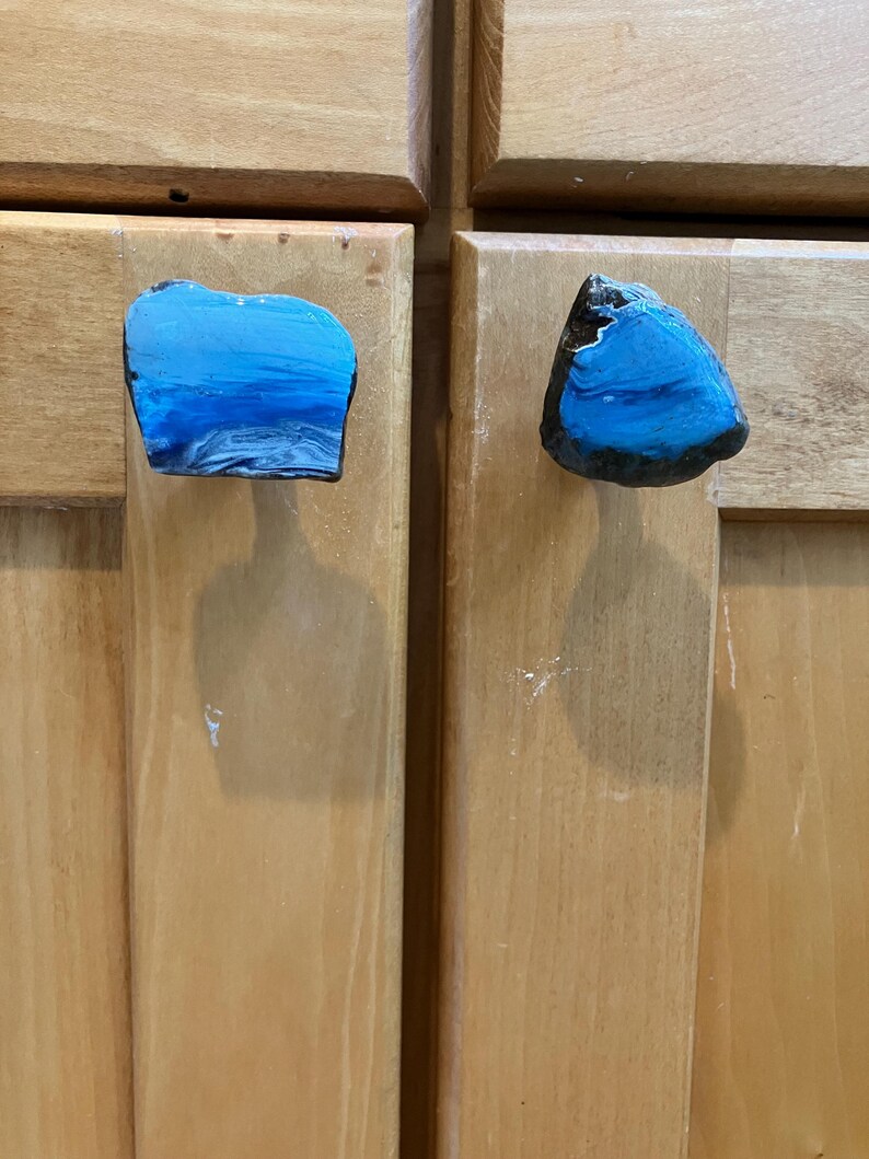 Peut inclure: Deux boutons de cabinet en r&eacute;sine bleue et noire avec un design abstrait unique. Les boutons sont en forme de roches plates irr&eacute;guli&egrave;res.
