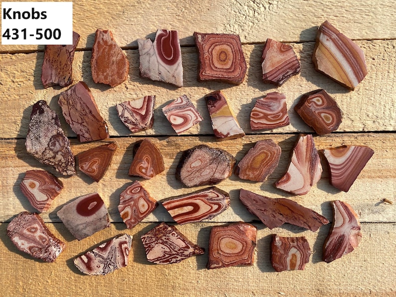 Op de afbeelding: Een verzameling van 25 gepolijste agaatstenen knoppen in rood, wit en bruin. De knoppen zijn van verschillende vormen en maten. Knoppen 431-500.