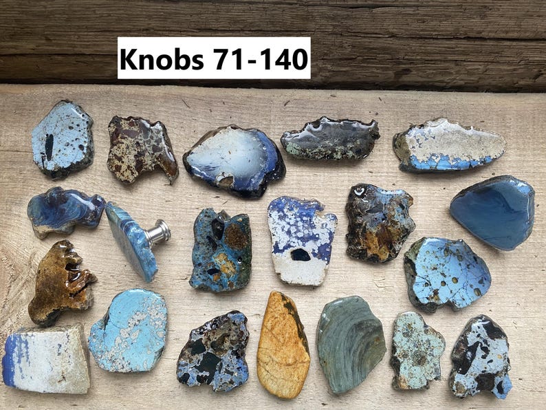 Peut inclure: Une collection de 18 boutons en c&eacute;ramique uniques dans diff&eacute;rentes nuances de bleu, marron et blanc. Les boutons sont de forme irr&eacute;guli&egrave;re et ont un aspect rustique et fait main. Le texte "Knobs 71-140" est visible en haut de l'image.