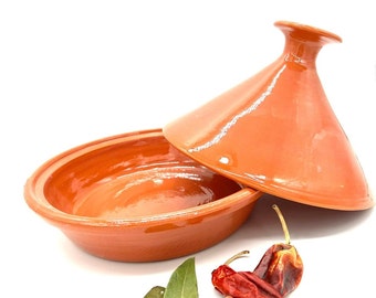 Tajine over cooking fire pot in handmade pottery oven in plain honey color.
