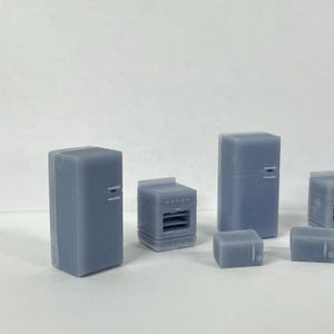 Puede incluir: Un conjunto de electrodom&eacute;sticos de cocina en miniatura, que incluye un refrigerador, un horno y dos electrodom&eacute;sticos m&aacute;s peque&ntilde;os, todos de color gris claro.