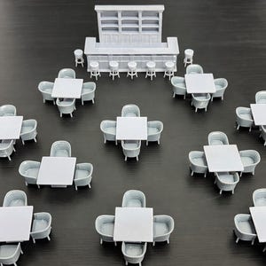 May include: A miniature restaurant scene featuring a bar with stools, tables, and chairs. The tables are square with four chairs each. The bar has shelves and is surrounded by stools. All items are light gray.