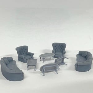 Puede incluir: Un conjunto de muebles grises para una sala de estar de casa de muñecas, que incluye un sofá, dos sillones y tres mesas de centro.