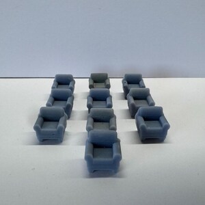 Op de afbeelding: Een set van 12 miniatuur blauwe fauteuils, perfect voor een poppenhuis of een miniatuur scène.