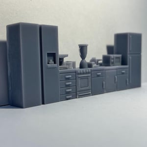 May include: A miniature model kitchen set with two refrigerators, a stove, an oven, and cabinets. The set is made of gray plastic and is about 10 inches long.