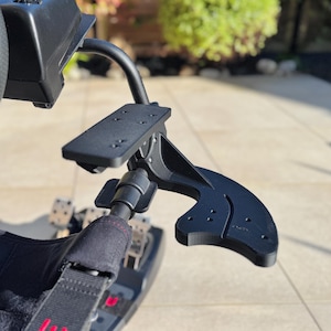 May include: A black metal racing wheel stand with a clamp-on arm for a phone or tablet. The stand is designed to be mounted to a racing simulator cockpit.
