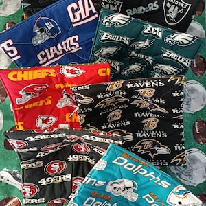 May include: A set of ten colorful pot holders featuring various NFL team logos, including the Chiefs, Giants, Eagles, Ravens, Dolphins, 49ers, and Raiders. The pot holders are made of fabric and have a quilted design.